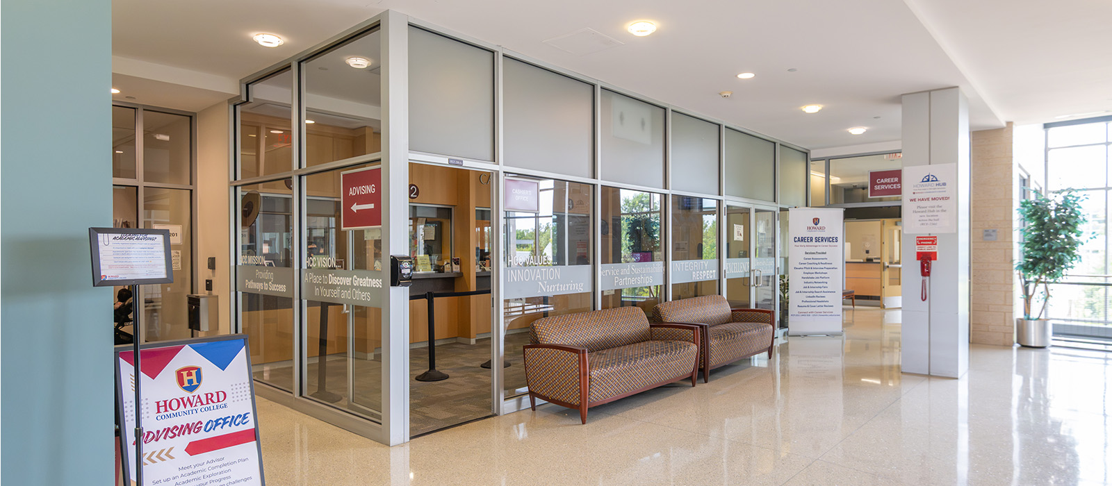 Howard Community College Cashier area with glass-fronted offices, seating and directional signs.