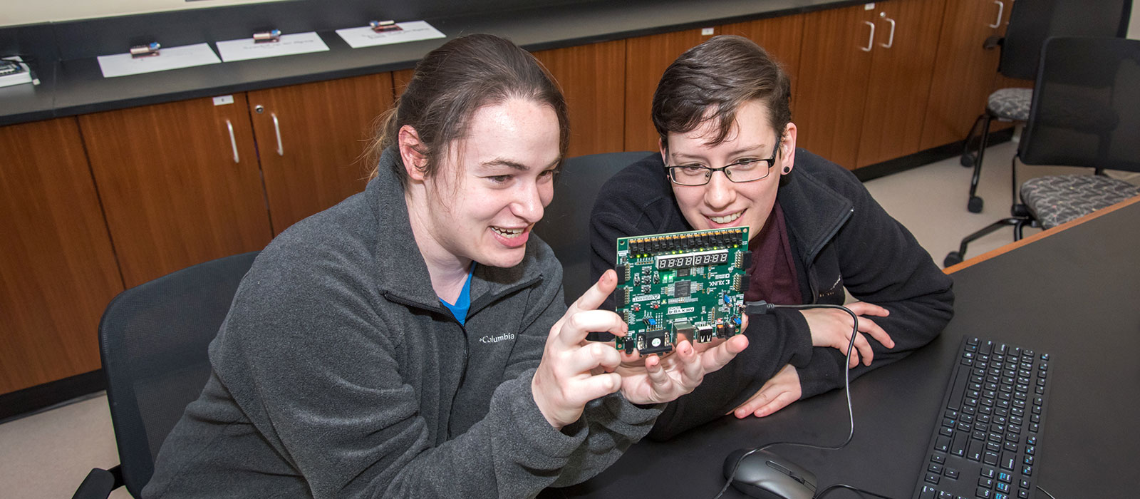Two students looking at a circuit board