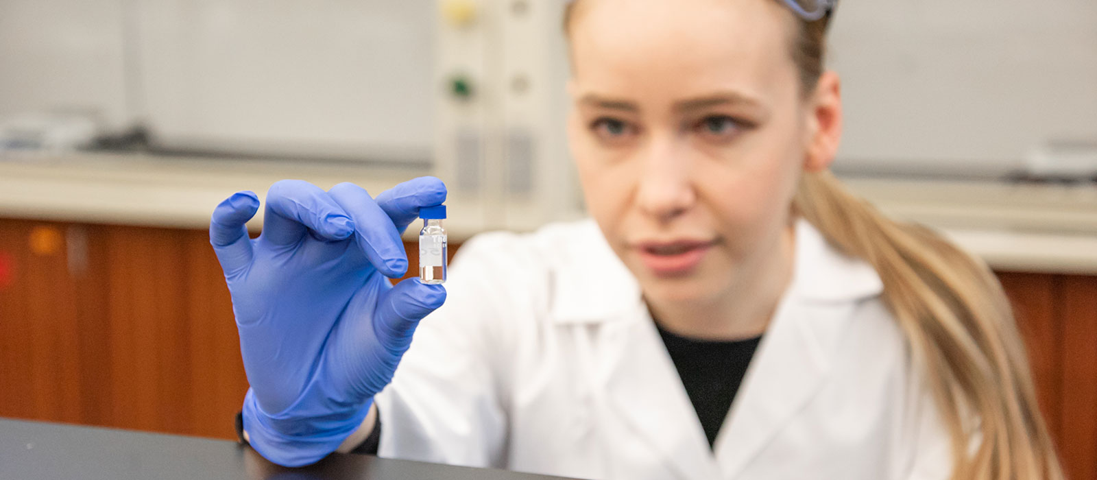 Student examining a small vial of clear fluid